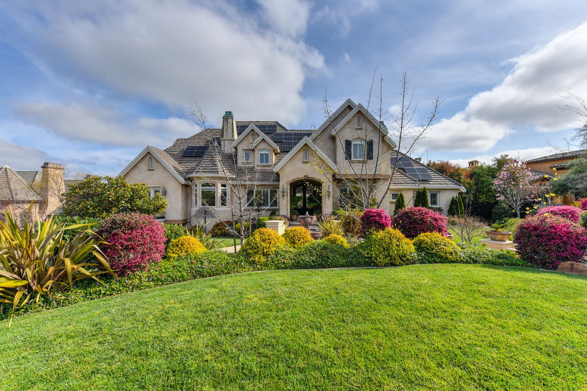A beautifully landscaped Dallas home with a lush green lawn and colorful flower beds